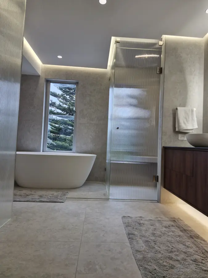 Freestanding bathtub beneath a window with a pine tree outlook