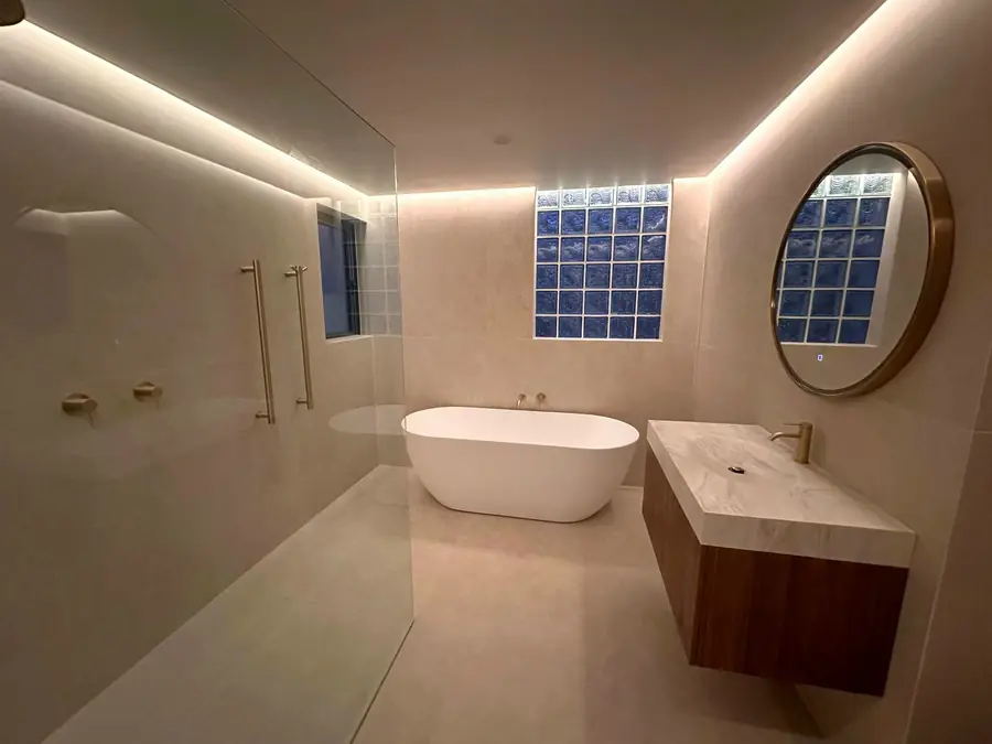 Bathroom with a glass block feature window and round brass mirror