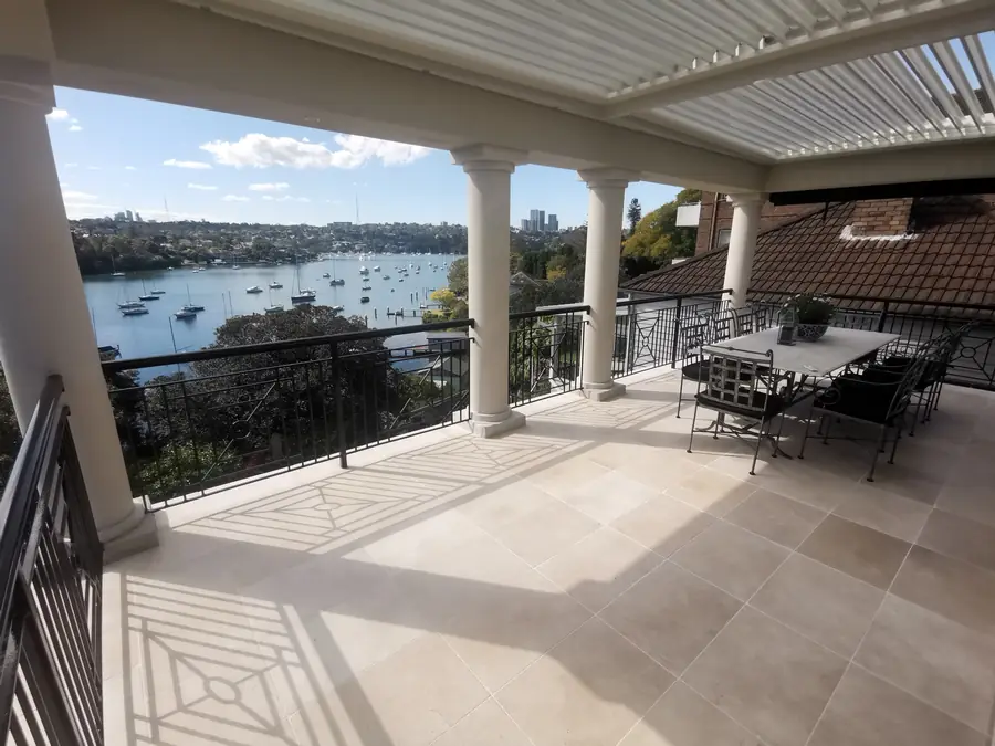 Large-format travertine terrace tiling with a harbour and boat view in Sydney